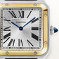 ساعة سانتوس-دومون كبيرة الحجم 43.5 مم × 31.4 مم، مصنوعة من الفولاذ وذهب أصفر، تاج أزرق، ميناء فضي بنمط أشعة الشمس، مع حزام من جلد التمساح باللون الرمادي الأنثراسيت، تعمل بحركة كوارتز.