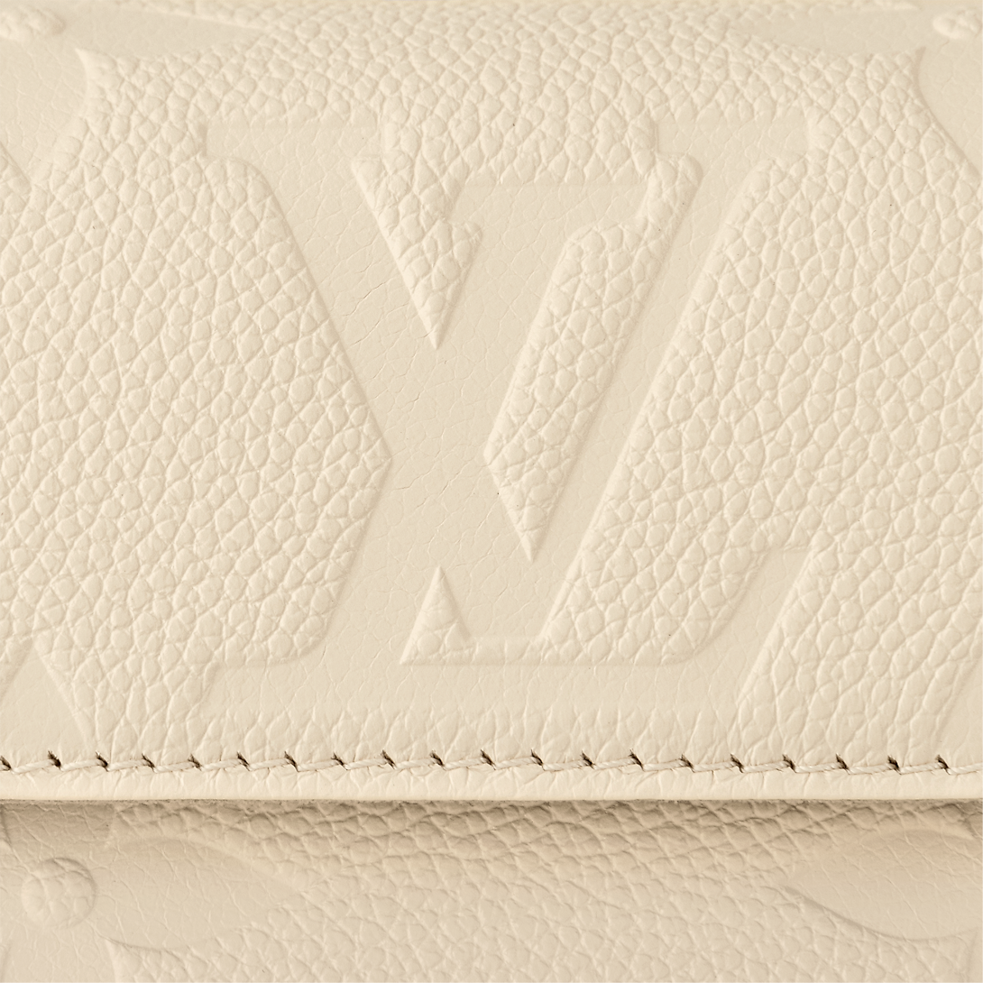 حقيبة Ivy Wallet on Chain بنقش Monogram Empreinte باللون الكريمي، تُحمل بوضعية كروس بودي
